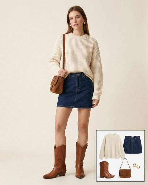 Woman wearing cognac leather cowboy boots with a dark denim mini skirt, a cream oversized chunky sweater and a brown suede shoulder bag