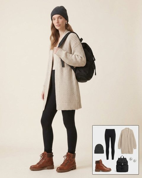 Woman wearing cognac lace-up hiker boots with black leggings, a long oatmeal cardigan, a charcoal beanie and a black backpack
