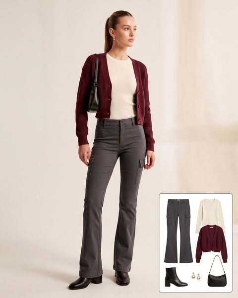 Woman wearing charcoal flare cargo pants with a cream ribbed top, a burgundy cropped cardigan, black block-heel ankle boots and a black shoulder bag