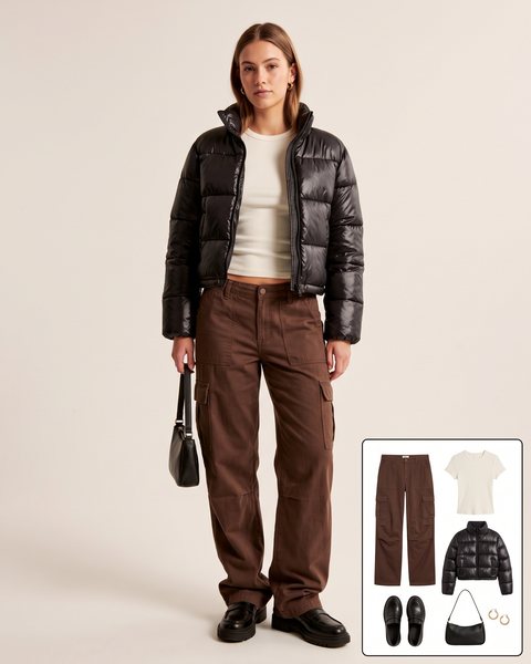 Woman wearing chocolate brown baggy cargo pants with an ivory ribbed tee, a cropped black puffer jacket, chunky black loafers and a small black shoulder bag