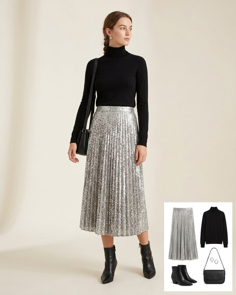 Woman wearing a silver sequin pleated midi skirt with a black turtleneck, black pointed ankle boots and a black crossbody bag