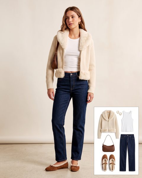 Woman wearing a cream chunky knit cardigan with faux fur trim over a white tank with dark stovepipe jeans, shearling ballet flats and a brown shoulder bag
