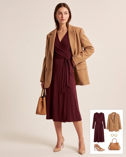 Burgundy jersey wrap dress with a tie waist layered under a camel oversized blazer worn open, with nude heels, a tan handbag and gold hoop earrings