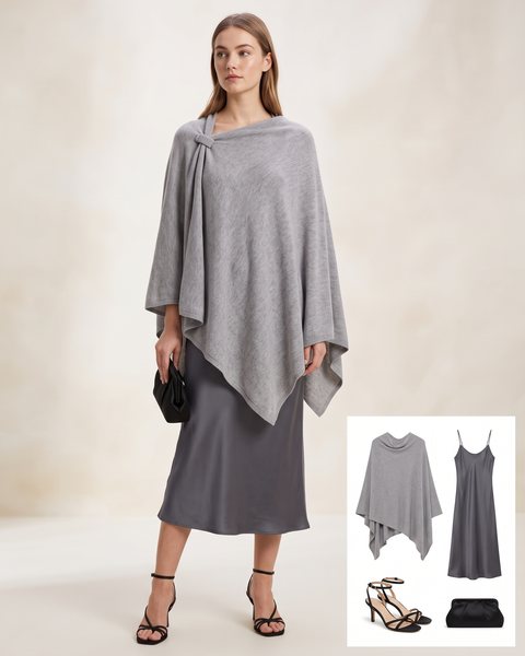 Grey draped wrap poncho with a shoulder clasp over a grey satin slip dress with black heels and a black clutch