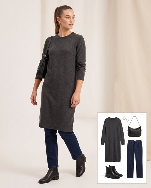Woman wearing a charcoal grey knee-length knit dress over dark straight-leg jeans with black Chelsea boots and a black shoulder bag