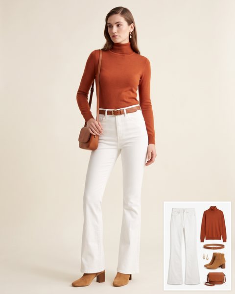 Woman wearing high-rise white flare jeans with a rust turtleneck, a cognac leather belt, tan suede block-heel ankle boots, a cognac crossbody bag and gold drop earrings