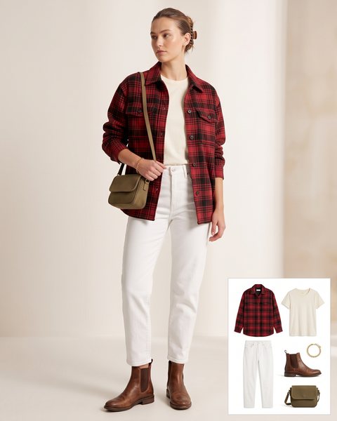 Woman wearing tapered white jeans with a cream tee, a red and black plaid shirt jacket, brown leather Chelsea boots, an olive crossbody bag and a gold chain bracelet
