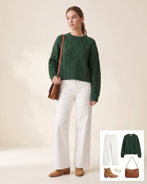 Woman wearing high-rise white wide-leg jeans with a forest green cable-knit sweater, tan suede ankle boots, a brown leather shoulder bag and gold hoop earrings