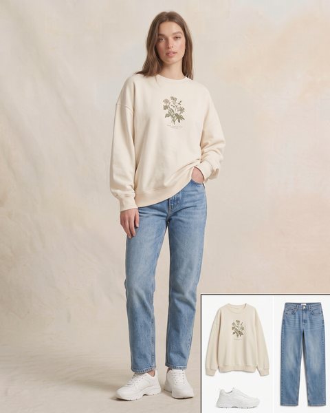 Krem oversize botanik desenli sweatshirt, açık mavi düz kesim kot pantolon ve beyaz spor ayakkabı ile hazırlanmış günlük oversize kombini